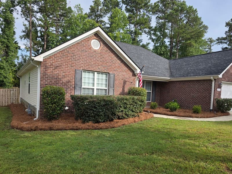 Brick home, freshly cut lawn, trimmed foundation shrubs